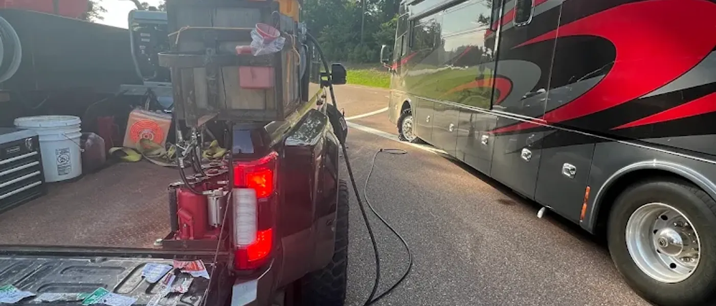 Breaux's Roadside service truck with tools and tire supplies laid out, parked alongside a Class A motorhome for on-site tire service
